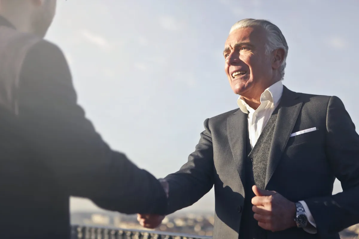 man in black suit shaking hands with another man